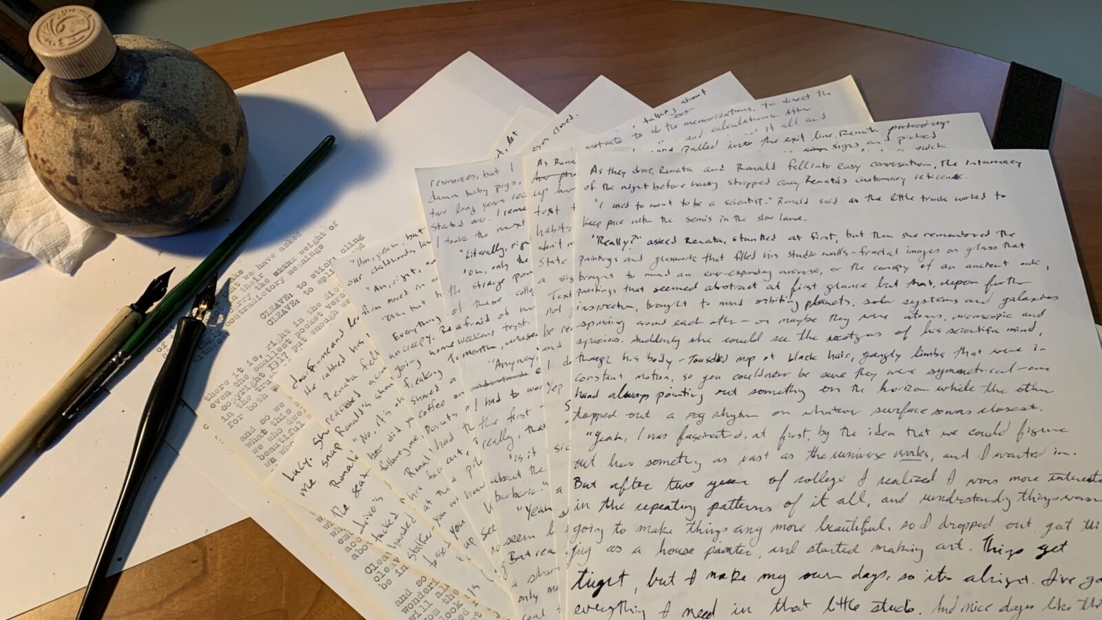 Photo of wooden desk with journal pages, fountain pen and ink
