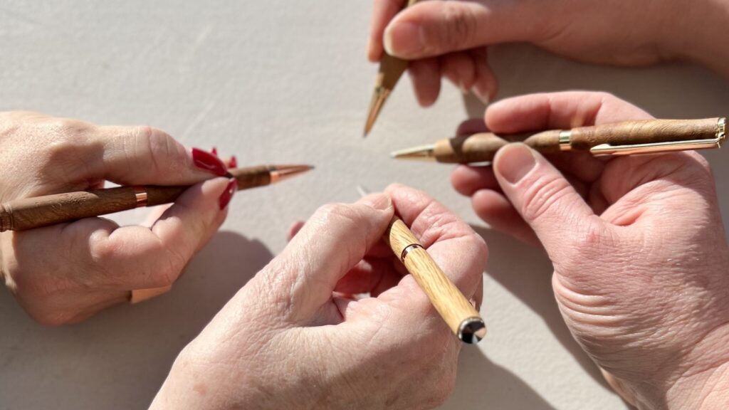 Photo of four different hands clustered together, each holding a fountain pen